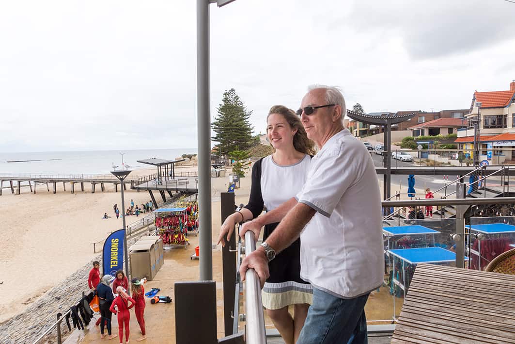 elderly man overlooking the beach with young lady
