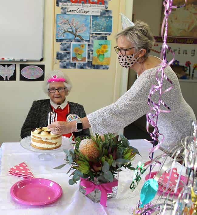 woman lighting birthday cake and centenarian looking 