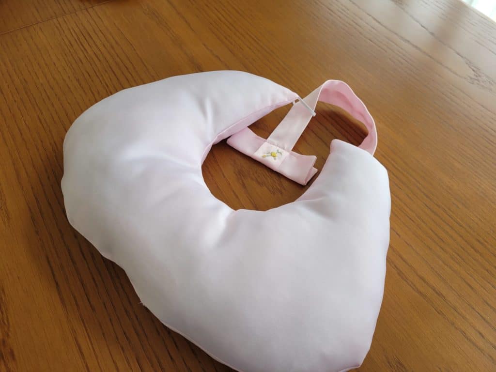 Light pink u shaped cushion with a small embroidered flower