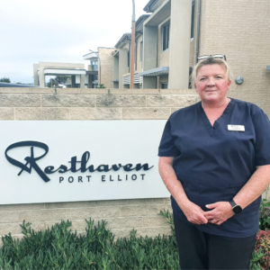 Claire Fox, Personal Care Assistant, stands next to the Resthaven Port Elliot sign