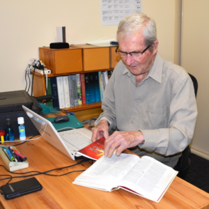 Mr Doug Parrington, Resthaven Bellevue Heights resident, reviewing a book at a wooden desk