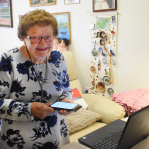 Olga Hrvatin in her residence holding her mobile phone with laptop next to her