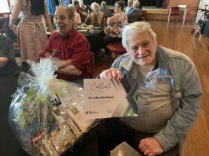 Older man with gift basket and first place certificate
