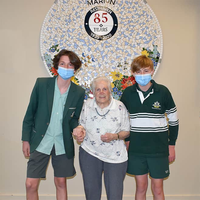 two male teenagers in school uniform with elderly lady standing in the middle