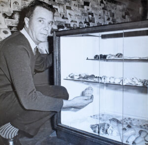 Black and white photograph of a young man with a shell collection