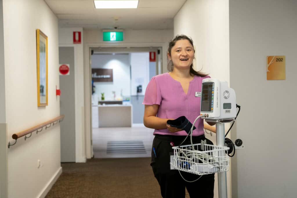 Nurse with equipment standing in aged care home hall