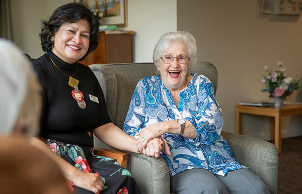 older lady holding hand of carer and smiling