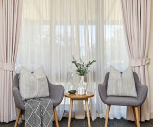 two armchairs and side table in front of cream curtain