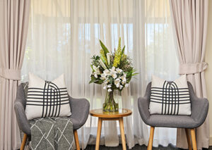two armchairs and side table in front of cream curtain