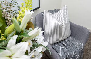 Grey armchair with white cushion and a side table with greenery and florals